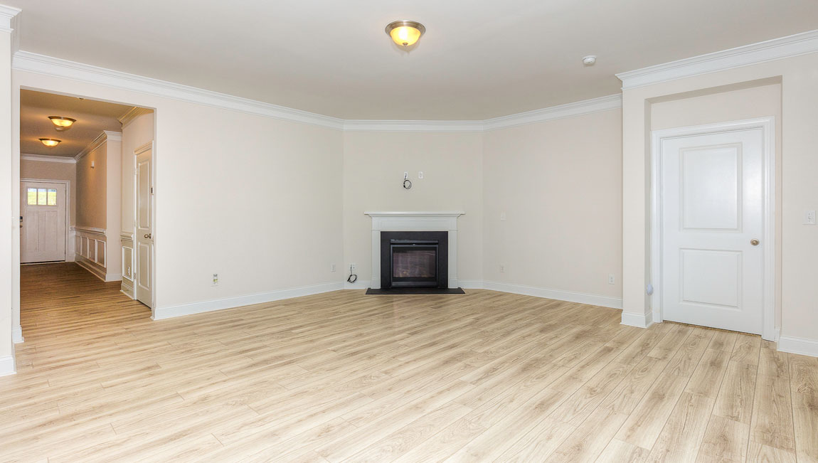 Open concept family room with wood floors, 3 large windows, and fireplace