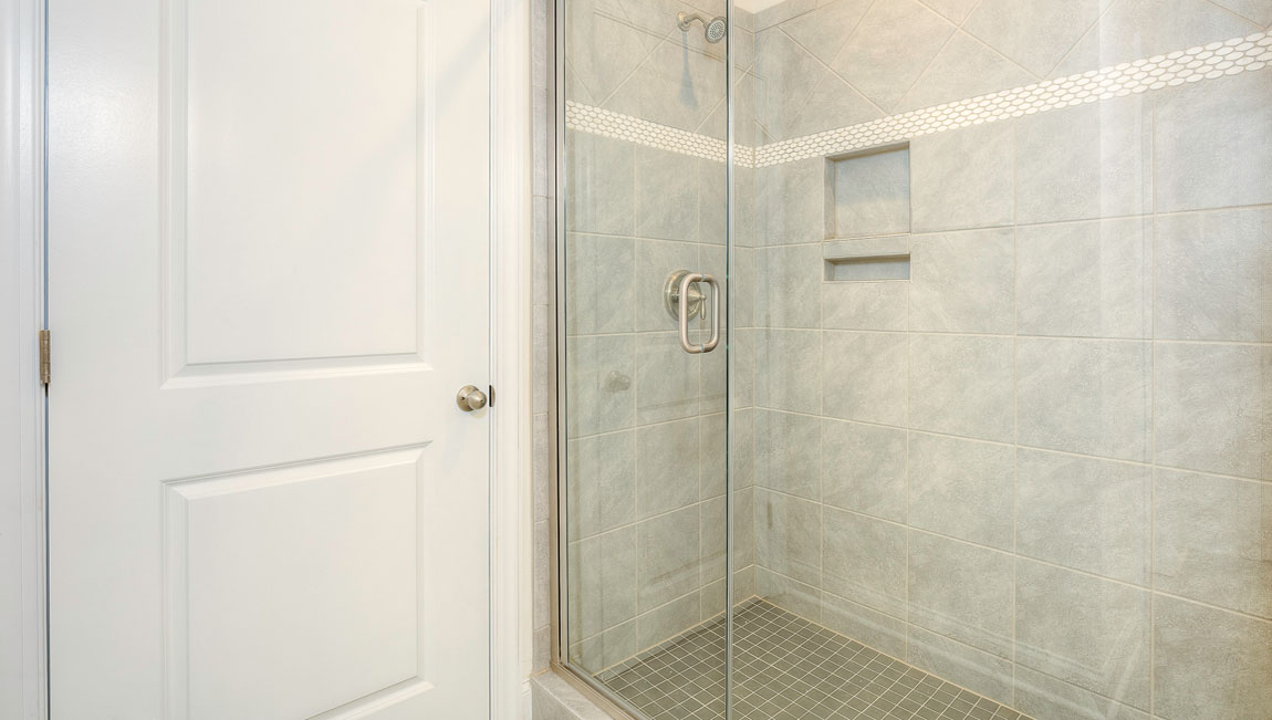 Primary bathroom with two sinks and counters, white cabinets, and wood floors