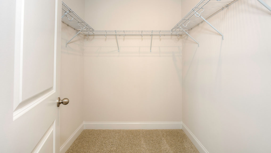 Carpeted walk in closet with built in hanger racks