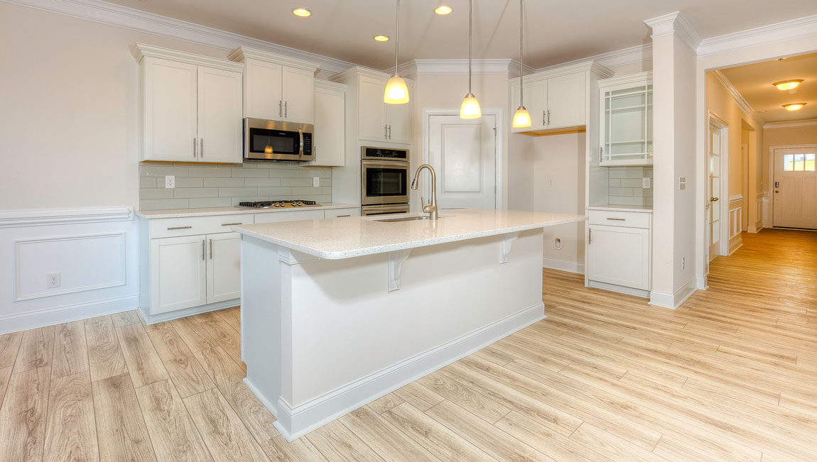 Kitchen and island with wood floors, white cabinets, quartz counters, and stainless steel appliances