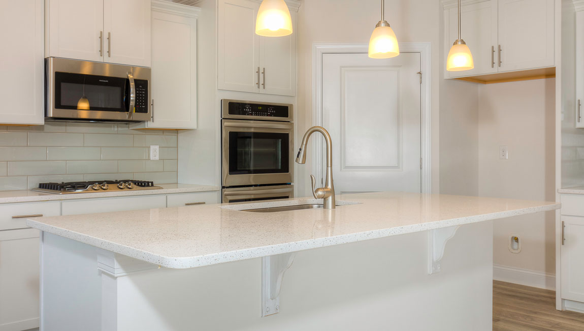 Kitchen and island with wood floors, white cabinets, quartz counters, and stainless steel appliances