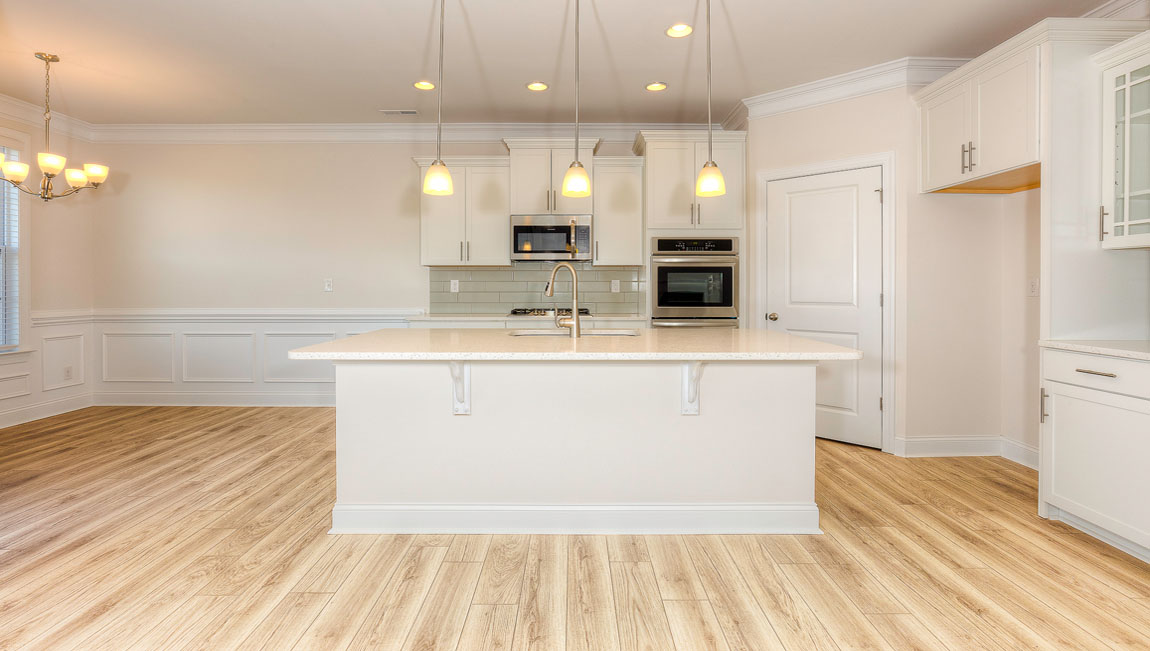 Kitchen and island with wood floors, white cabinets, quartz counters, and stainless steel appliances