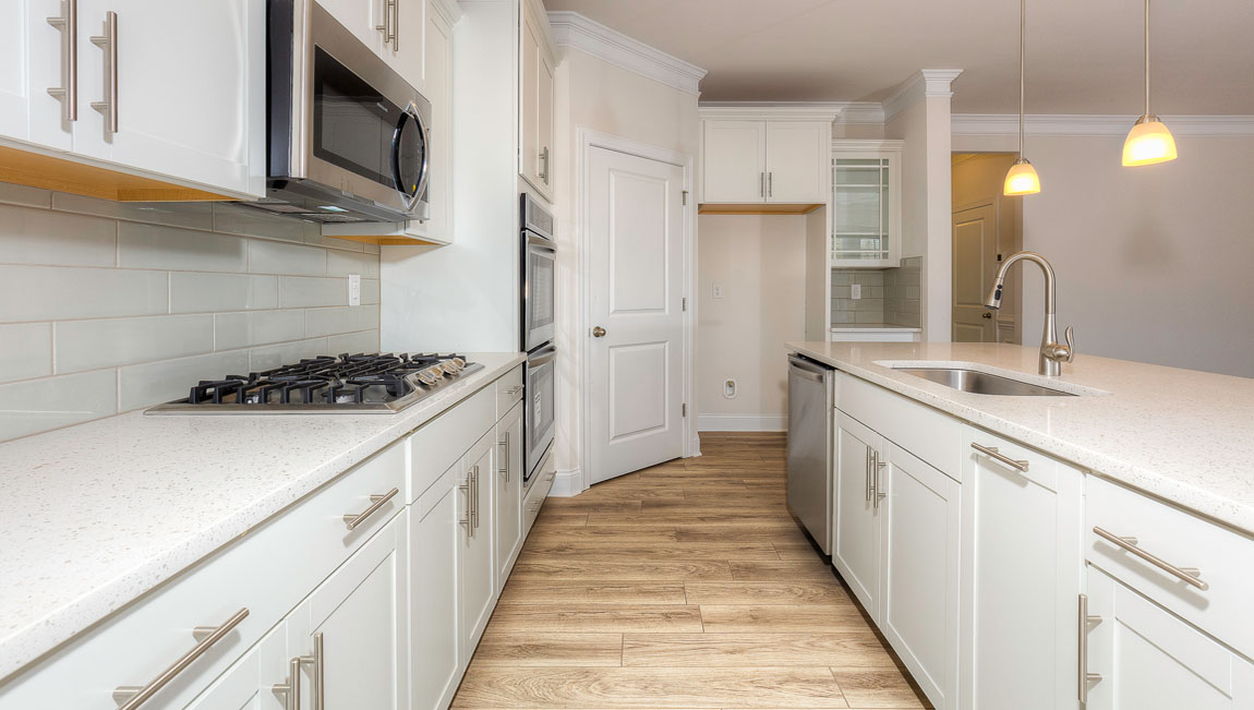 Kitchen and island with wood floors, white cabinets, quartz counters, and stainless steel appliances