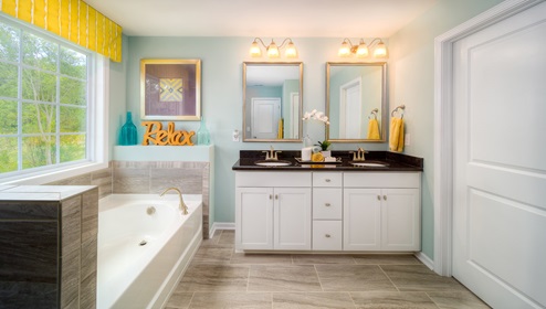 Primary bathroom with double sinks, bathtub and white cabinets