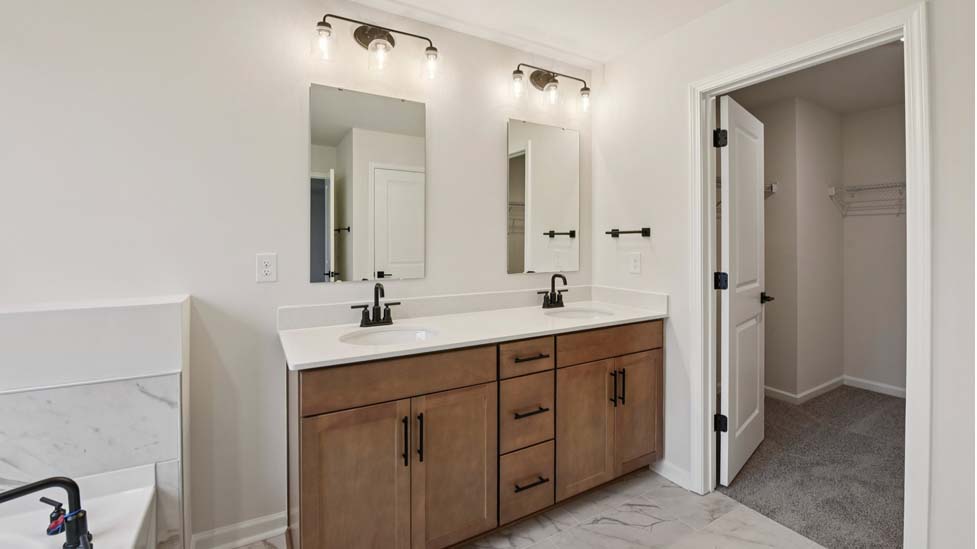Primary bathroom with white cabinets, bathtub, and glass door shower