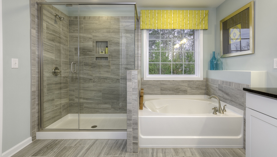 Primary bathroom with white cabinets, bathtub, and glass door shower