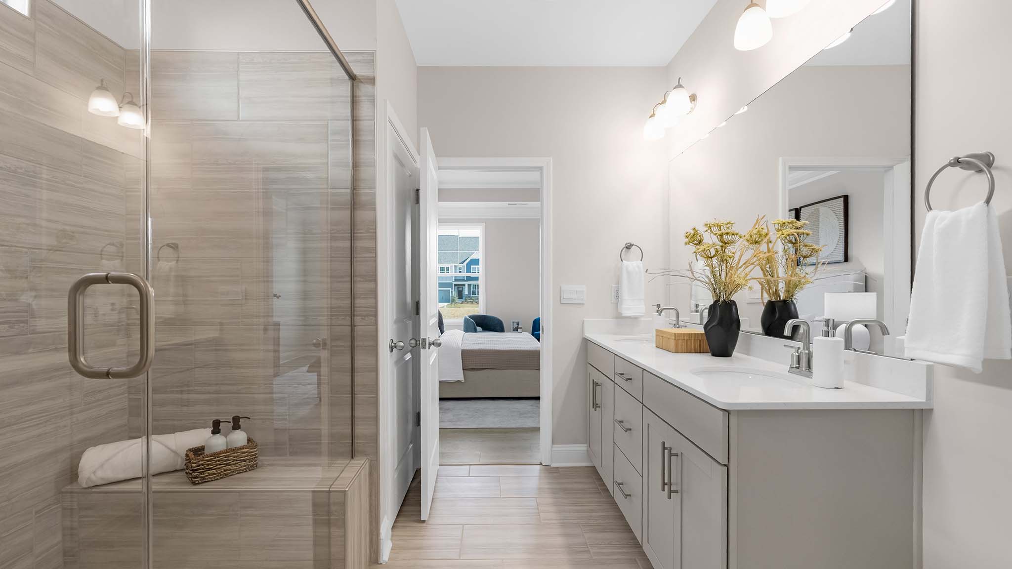 Primary bathroom with white cabinets, double sinks, and glass door shower