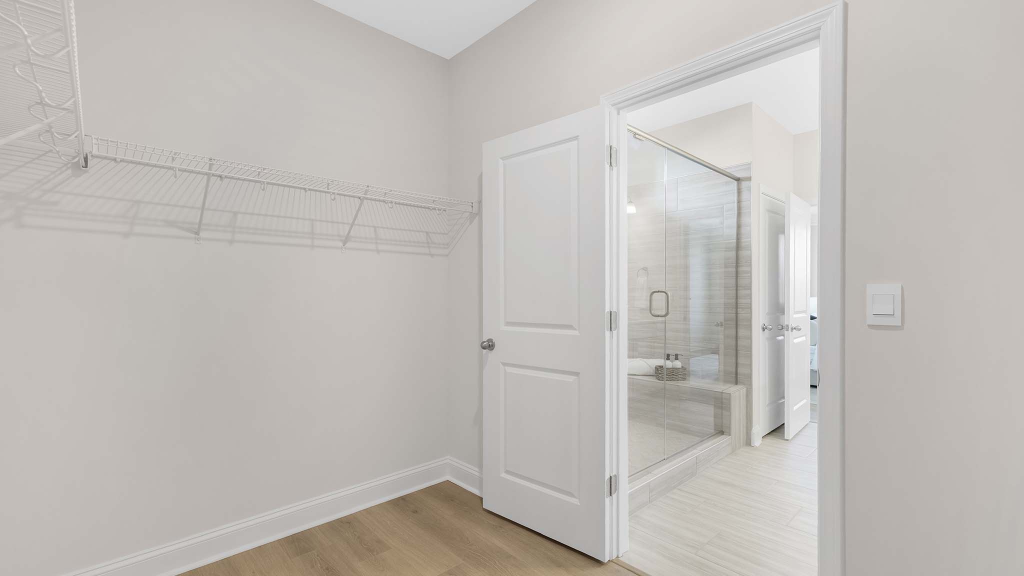 Primary bedroom walk in closet with built in racks for hanging