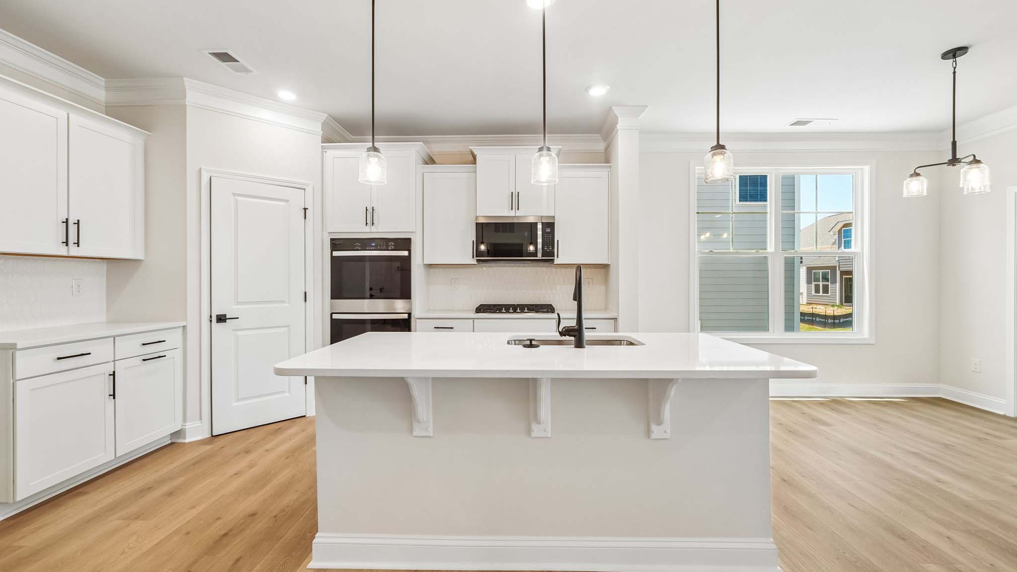Kitchen and island with wood floors, white cabinets, breakfast area on island bar, and stainless steel appliances