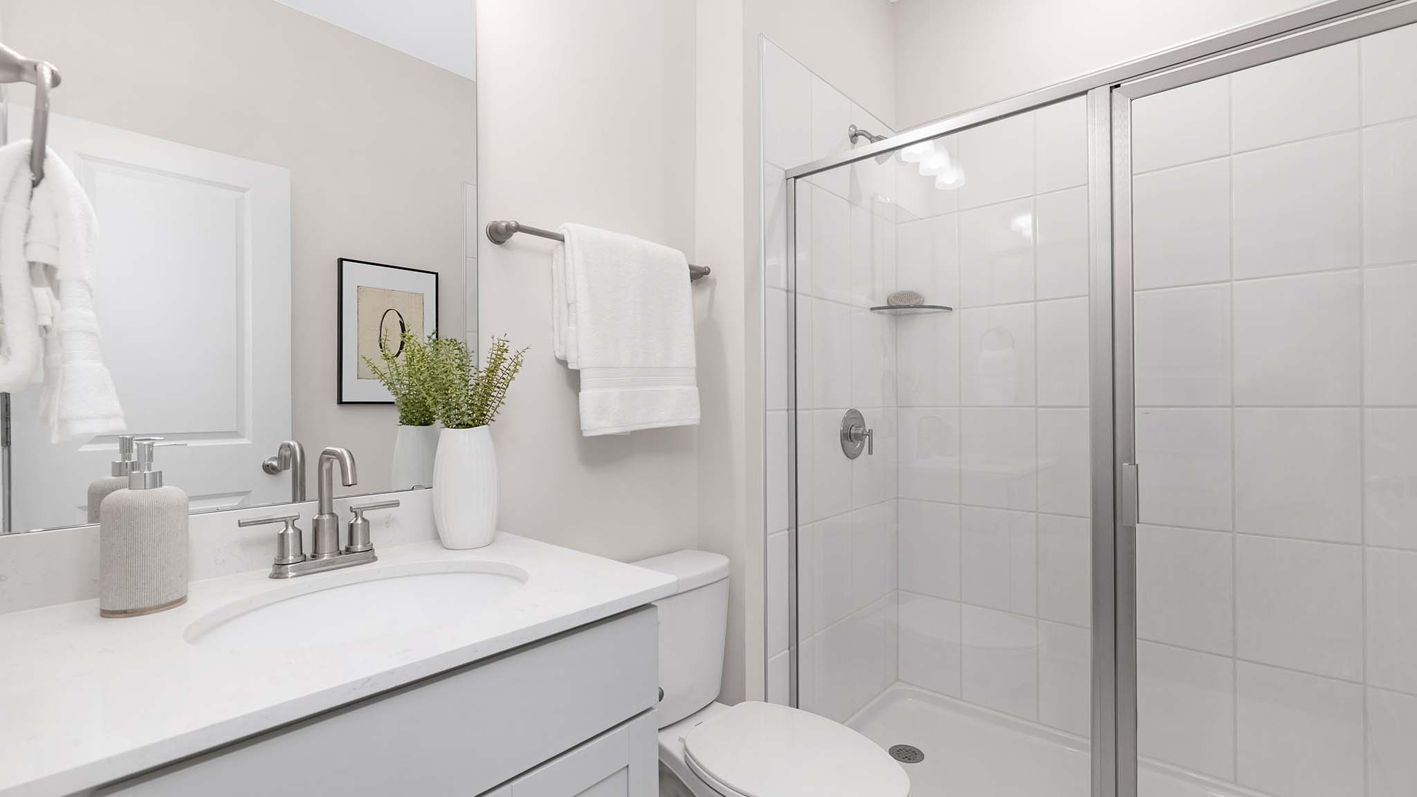 Bathroom with double sinks, white cabinets, and separate door to bathtub and toilet