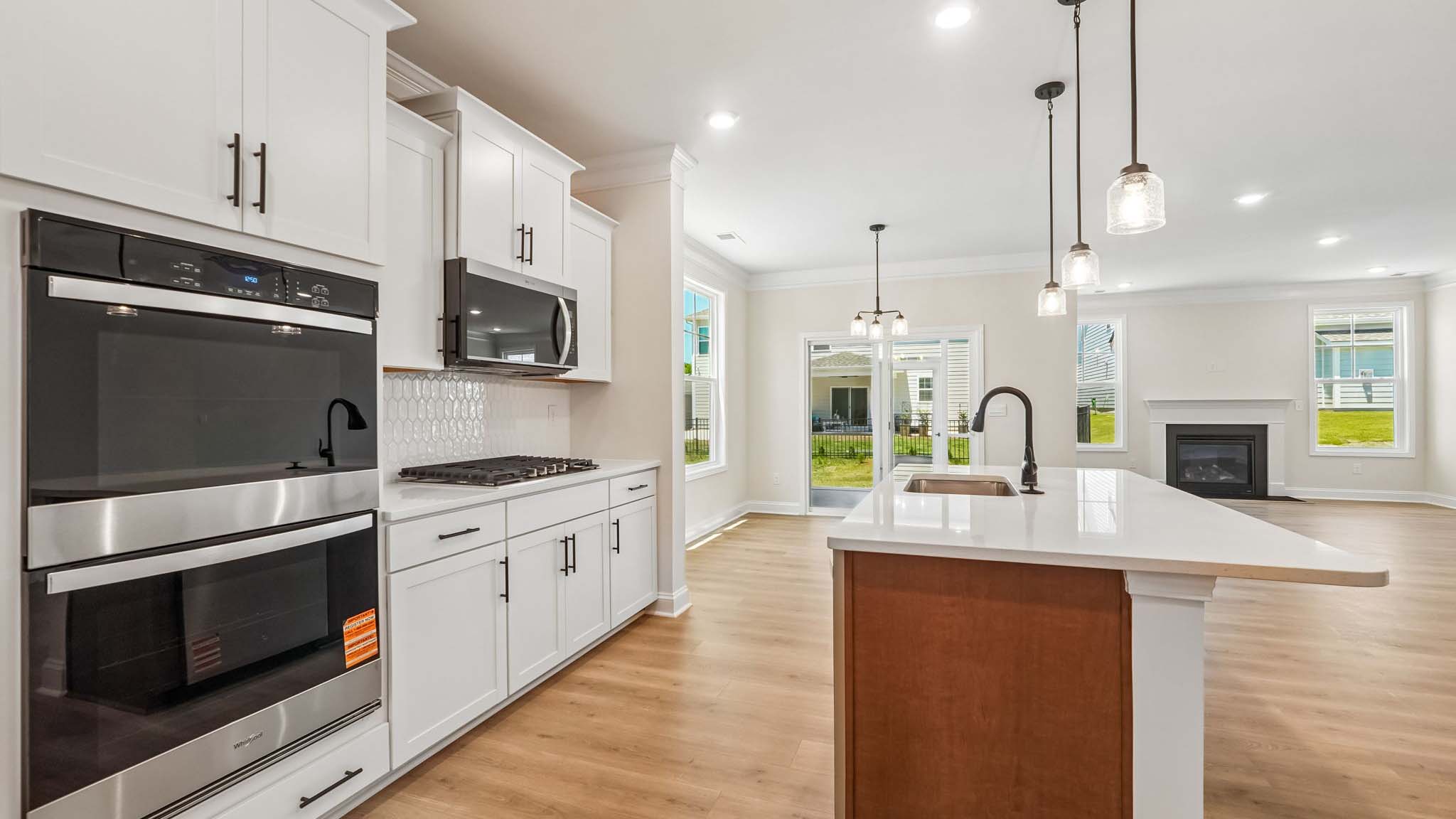 Kitchen and island with wood floors, white cabinets, breakfast area on island bar, and stainless steel appliances