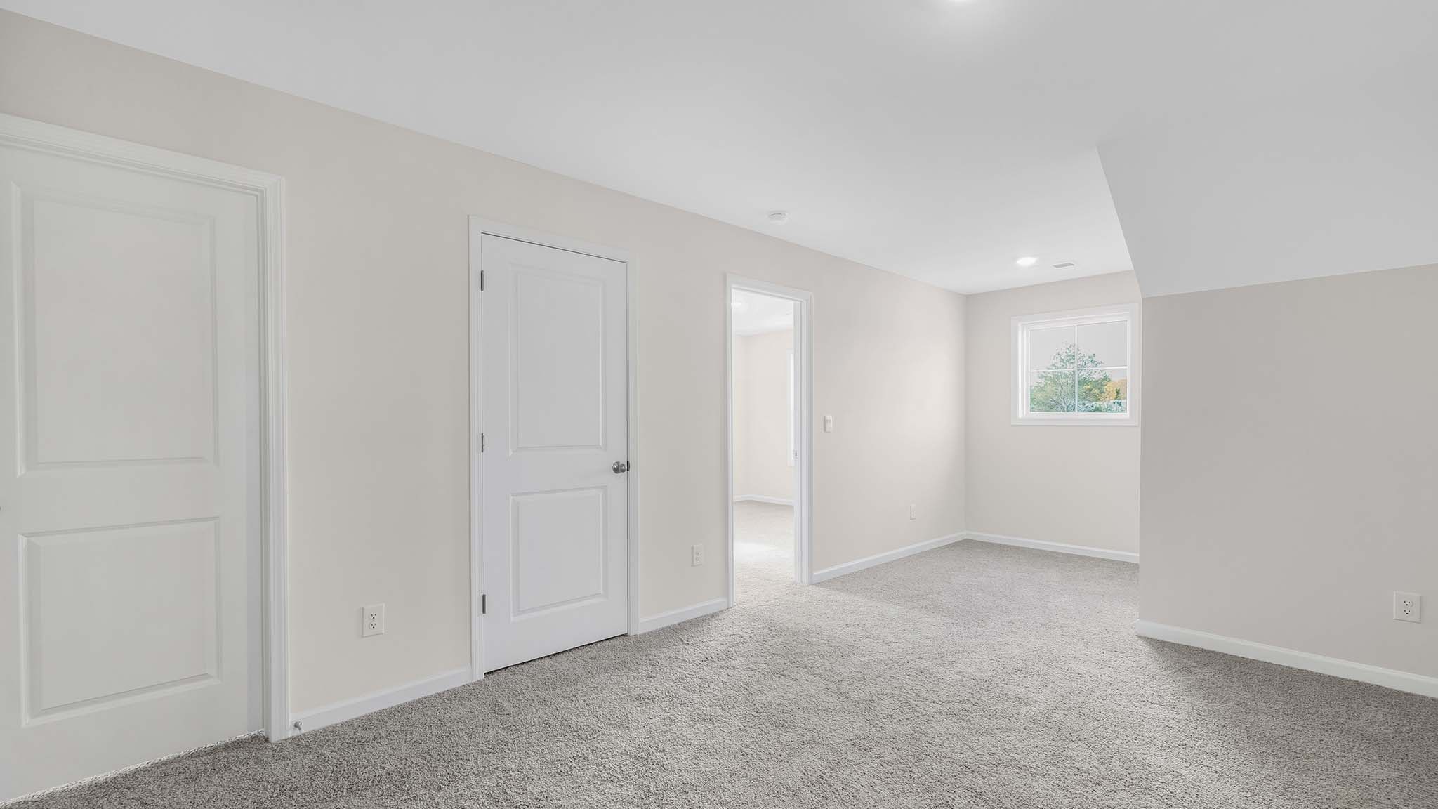 Upstairs carpeted loft space with small window