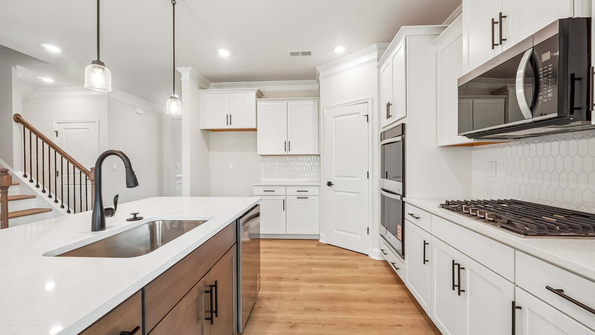 Kitchen and island with wood floors, white cabinets, breakfast area on island bar, and stainless steel appliances