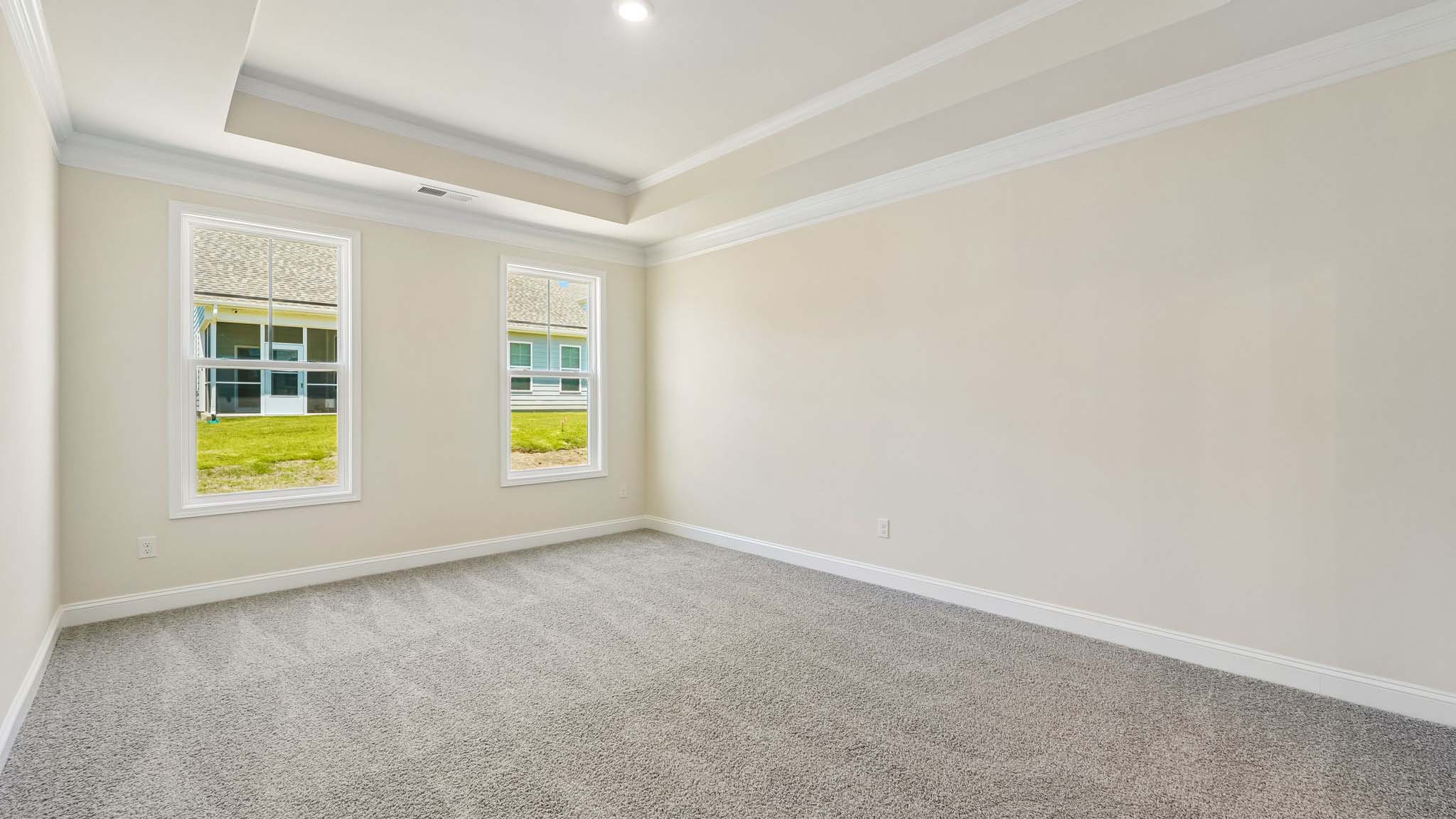 Primary bedroom with carpet, and two large windows