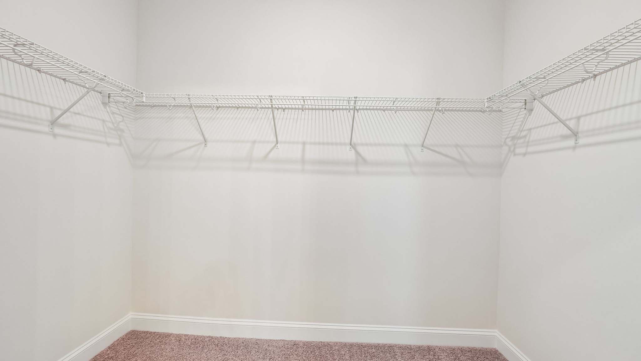 Primary bedroom walk in closet with built in racks for hanging