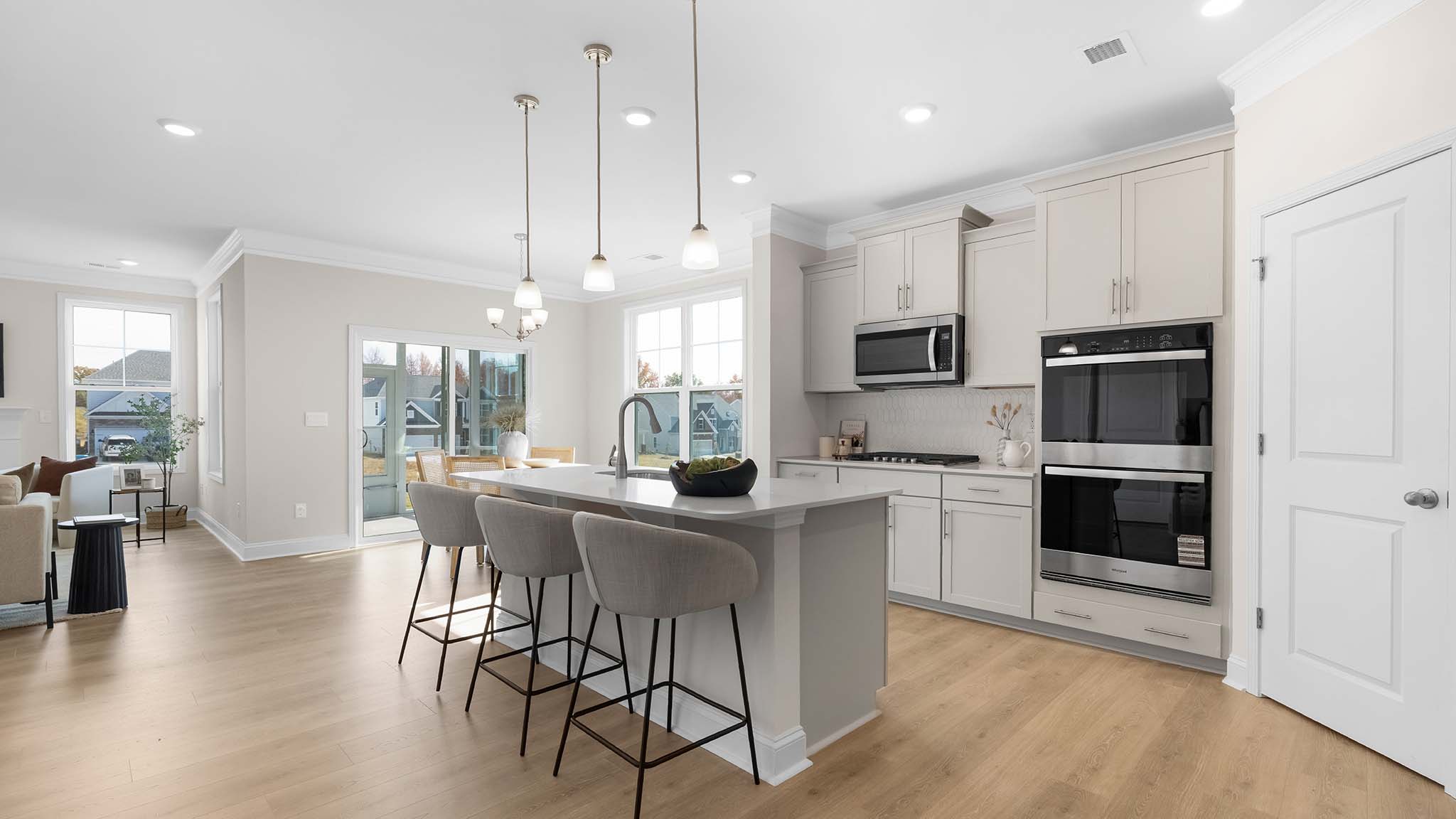 Kitchen and island with wood floors, white cabinets, breakfast area on island bar, and stainless steel appliances