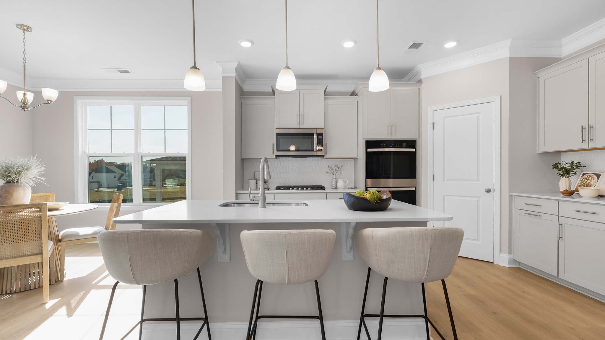 Kitchen and island with wood floors, white cabinets, breakfast area on island bar, and stainless steel appliances