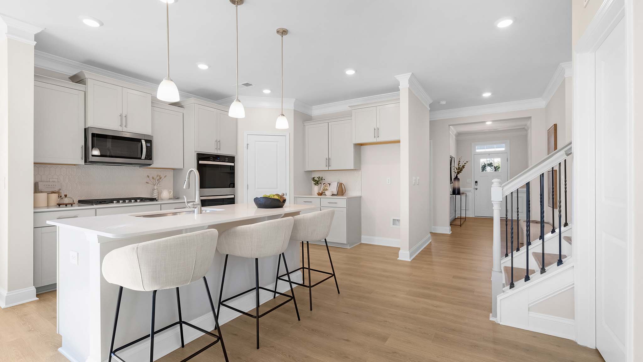 Kitchen and island with wood floors, white cabinets, breakfast area on island bar, and stainless steel appliances