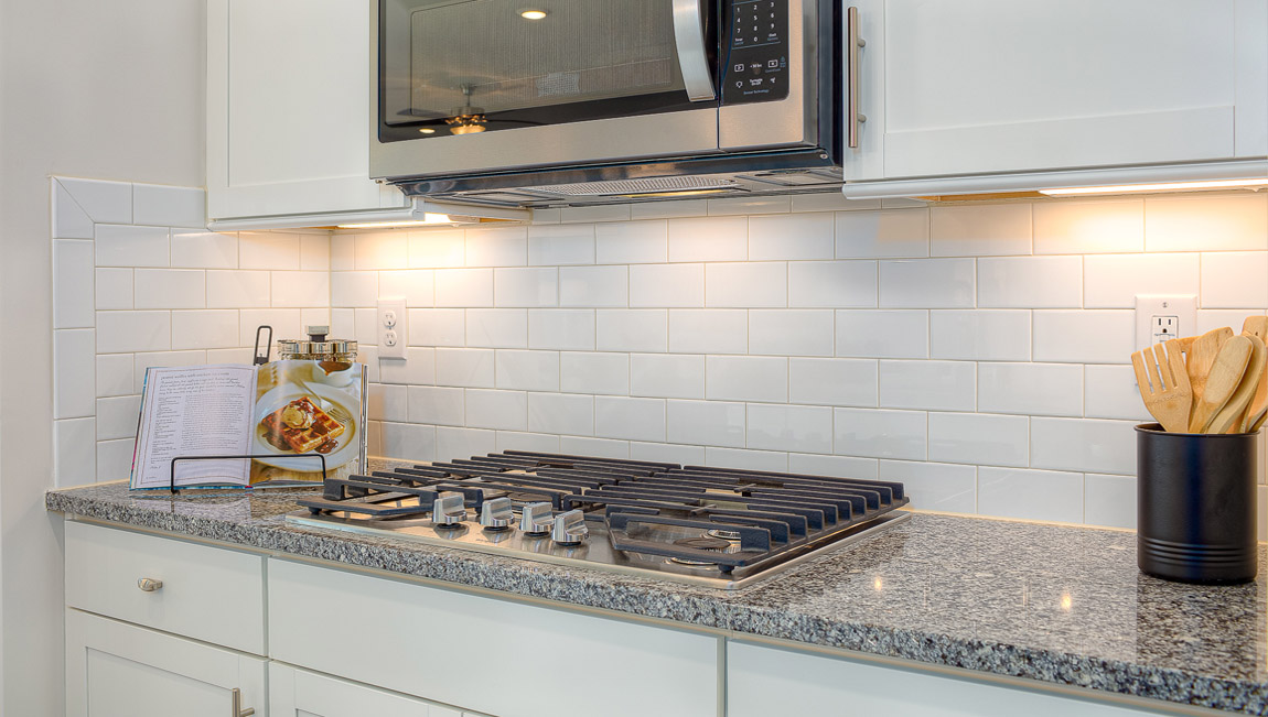 Kitchen and island with wood floors, white cabinets, breakfast area on island bar, and stainless steel appliances
