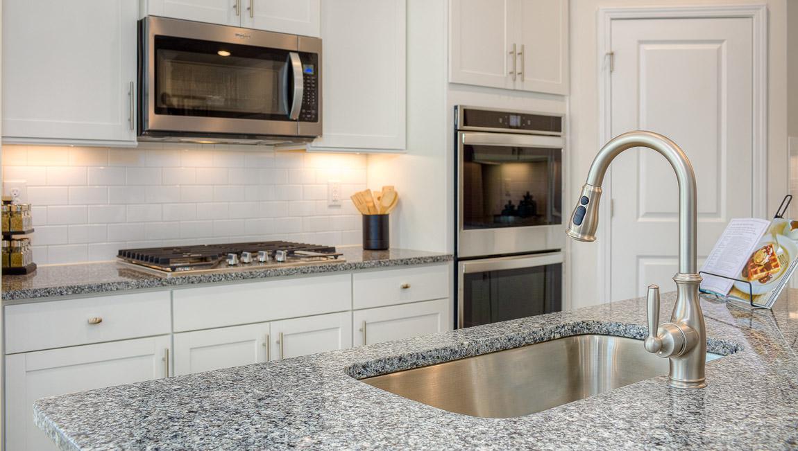 Kitchen and island with wood floors, white cabinets, breakfast area on island bar, and stainless steel appliances
