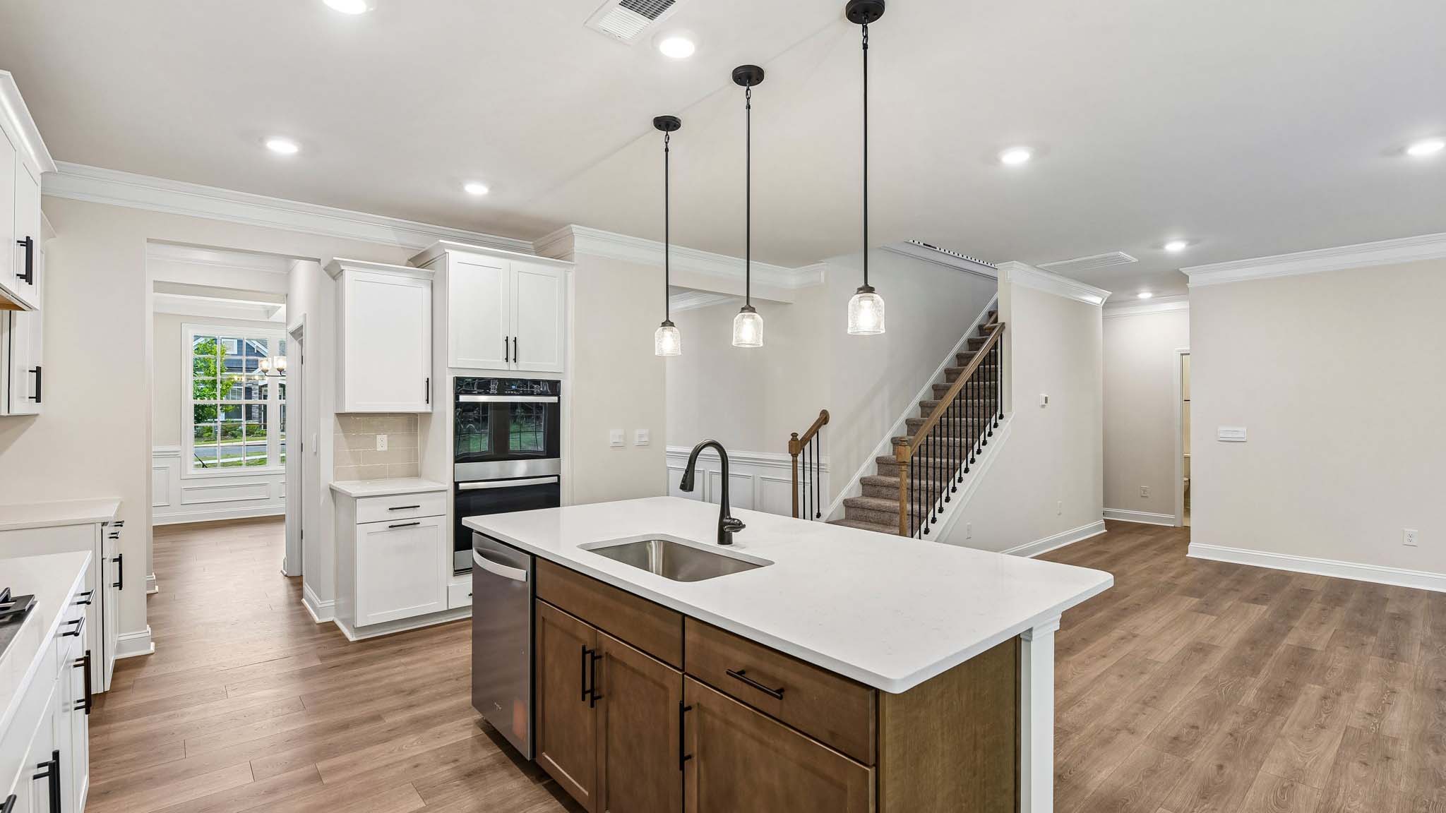 Kitchen and island with white cabinets and counters, wood floors, and stainless steel appliances