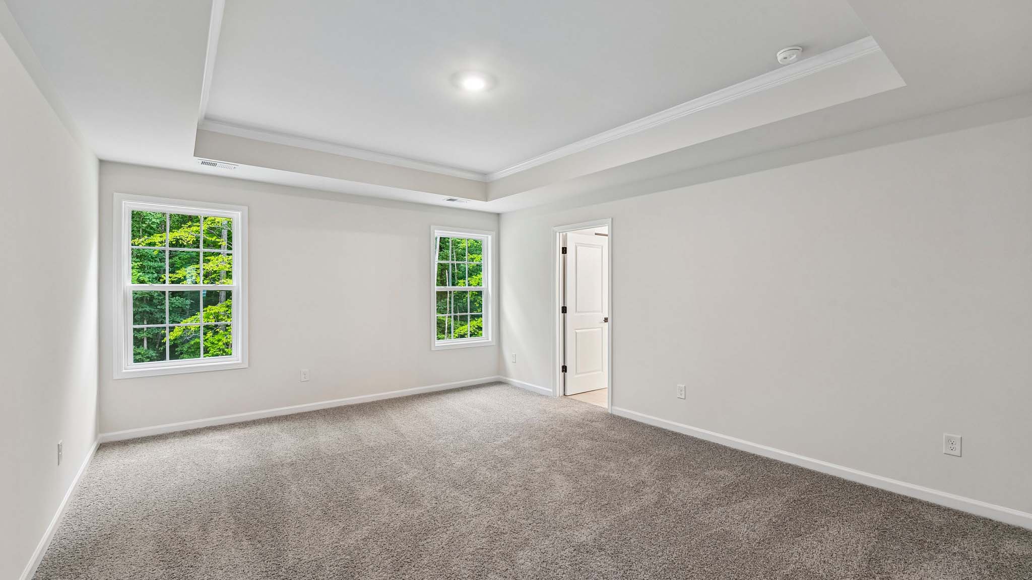 Primary carpeted bedroom with windows