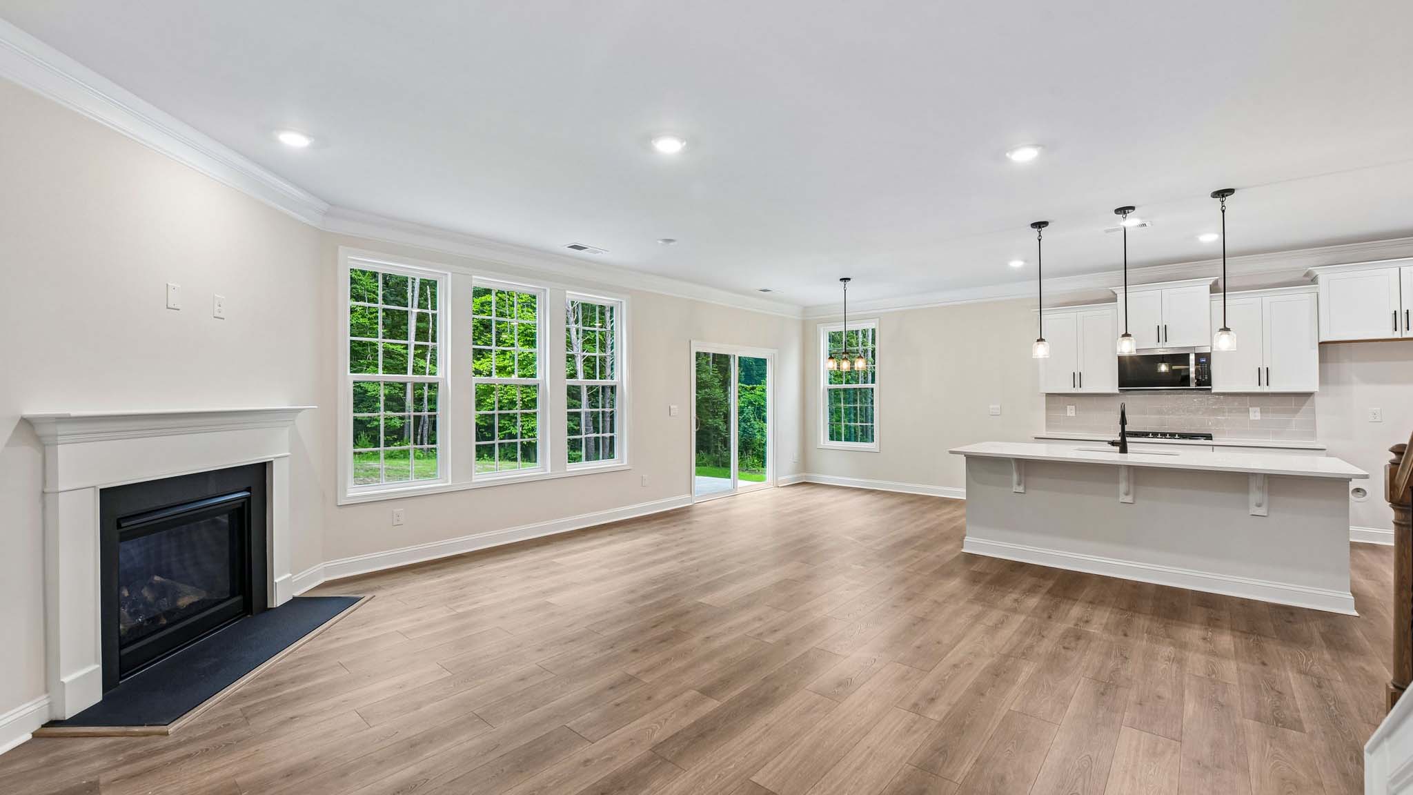 Living room space beside kitchen with wood floors and fireplace