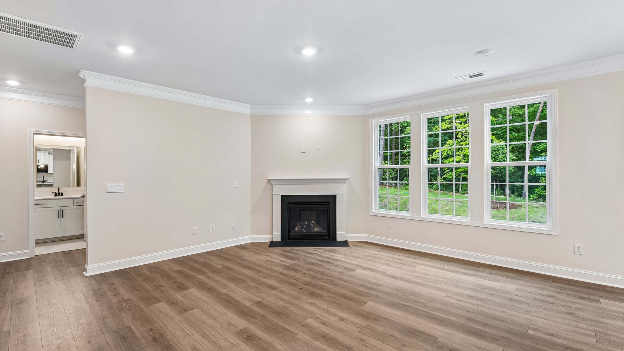 Living room space beside kitchen with wood floors and fireplace