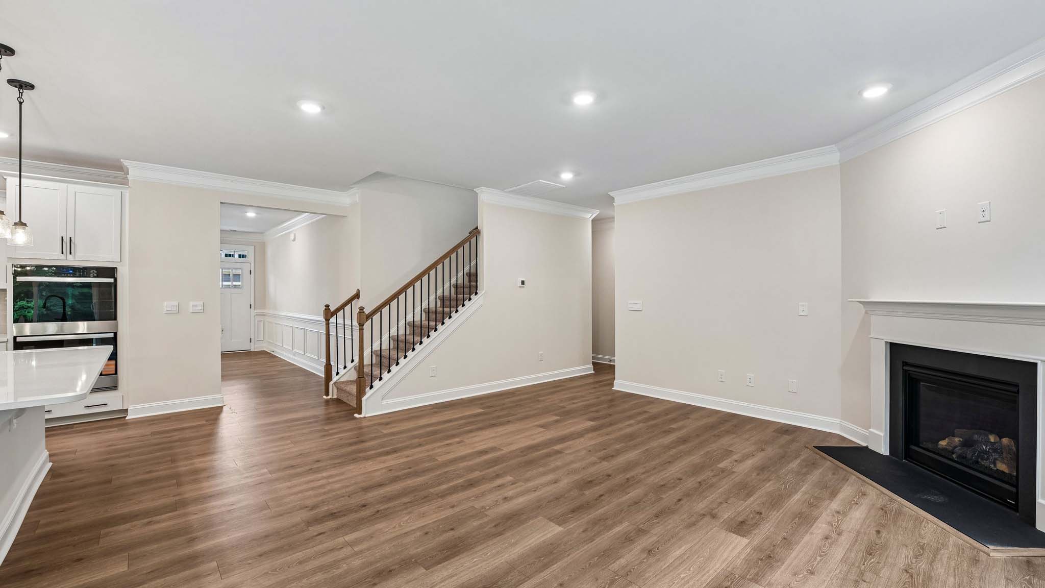 Living room space beside kitchen with wood floors and fireplace