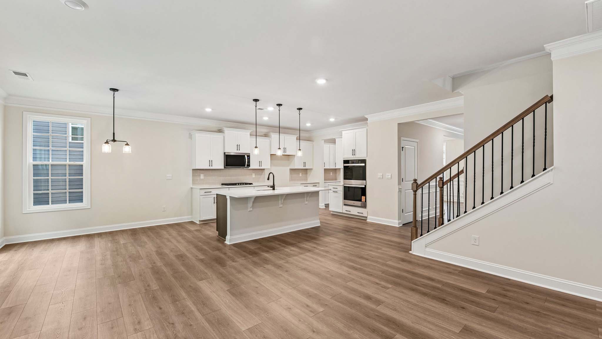 Living room space beside kitchen with wood floors and fireplace