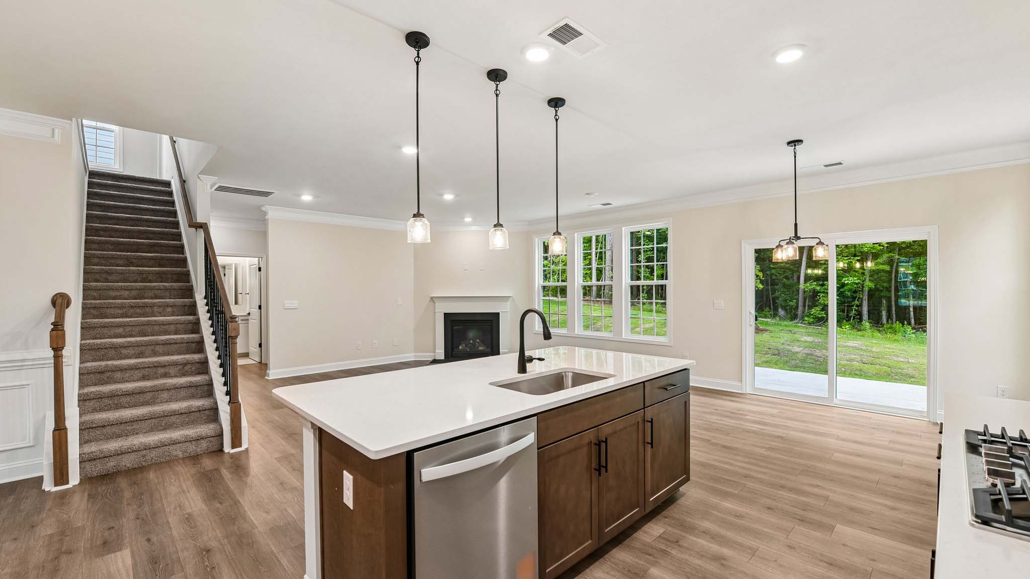 Kitchen and island with white cabinets and counters, wood floors, and stainless steel appliances