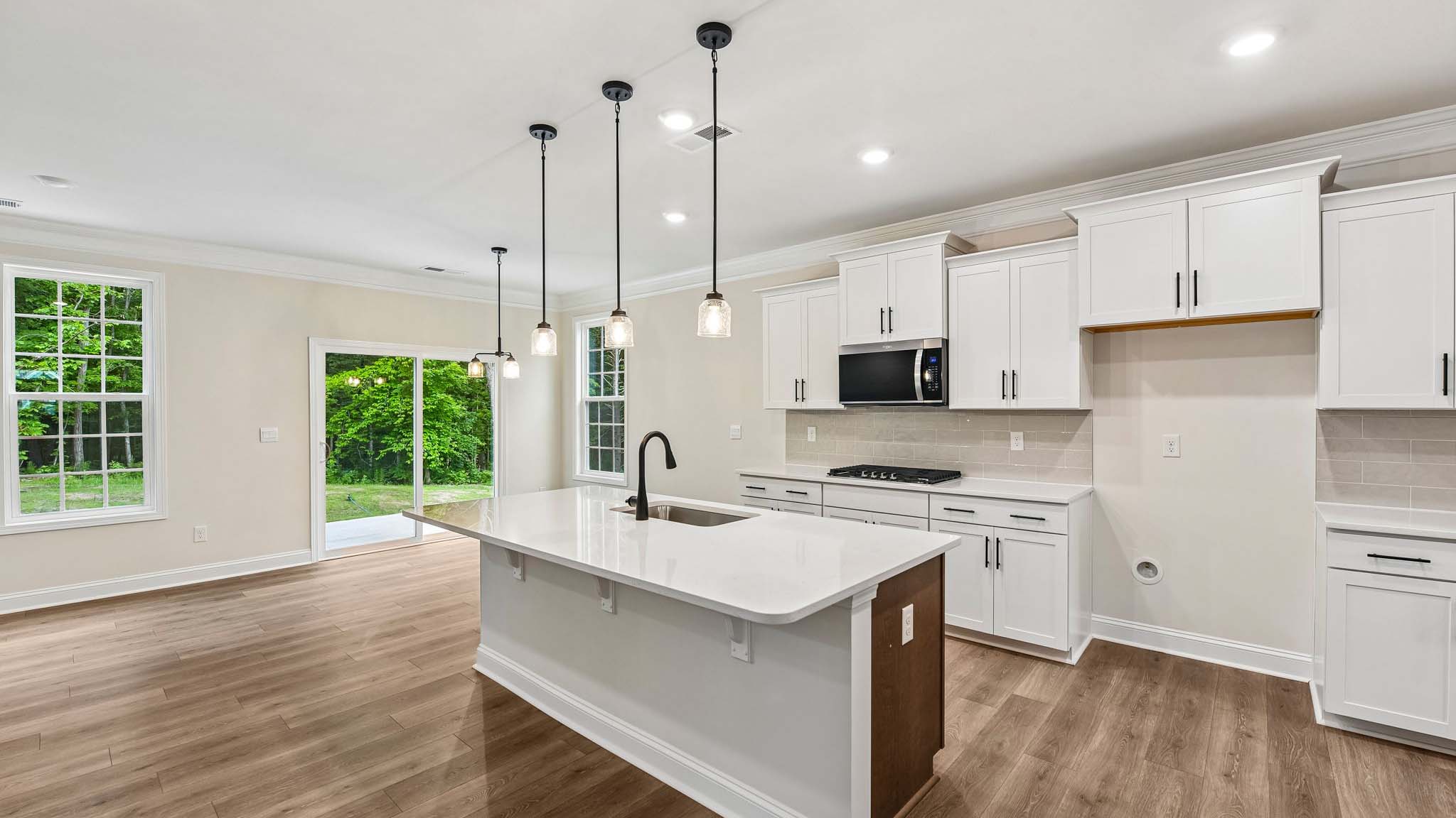 Kitchen and island with white cabinets and counters, wood floors, and stainless steel appliances