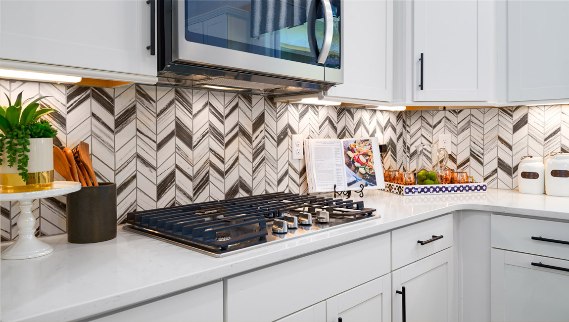 Kitchen and island with wood floors, white cabinets, quartz counters, and stainless steel appliances