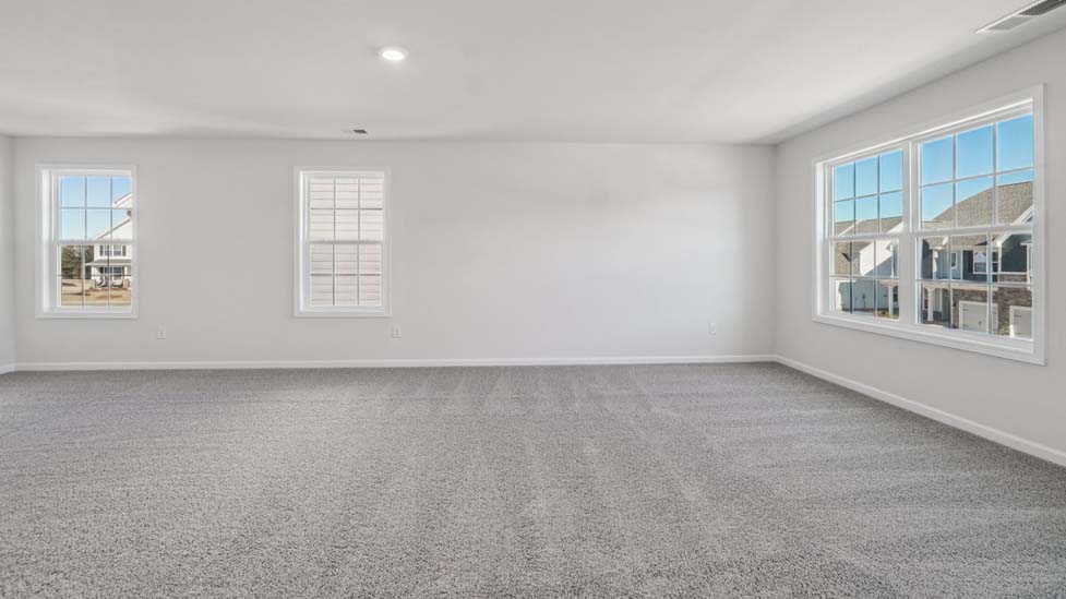 Primary carepeted bedroom with large windows