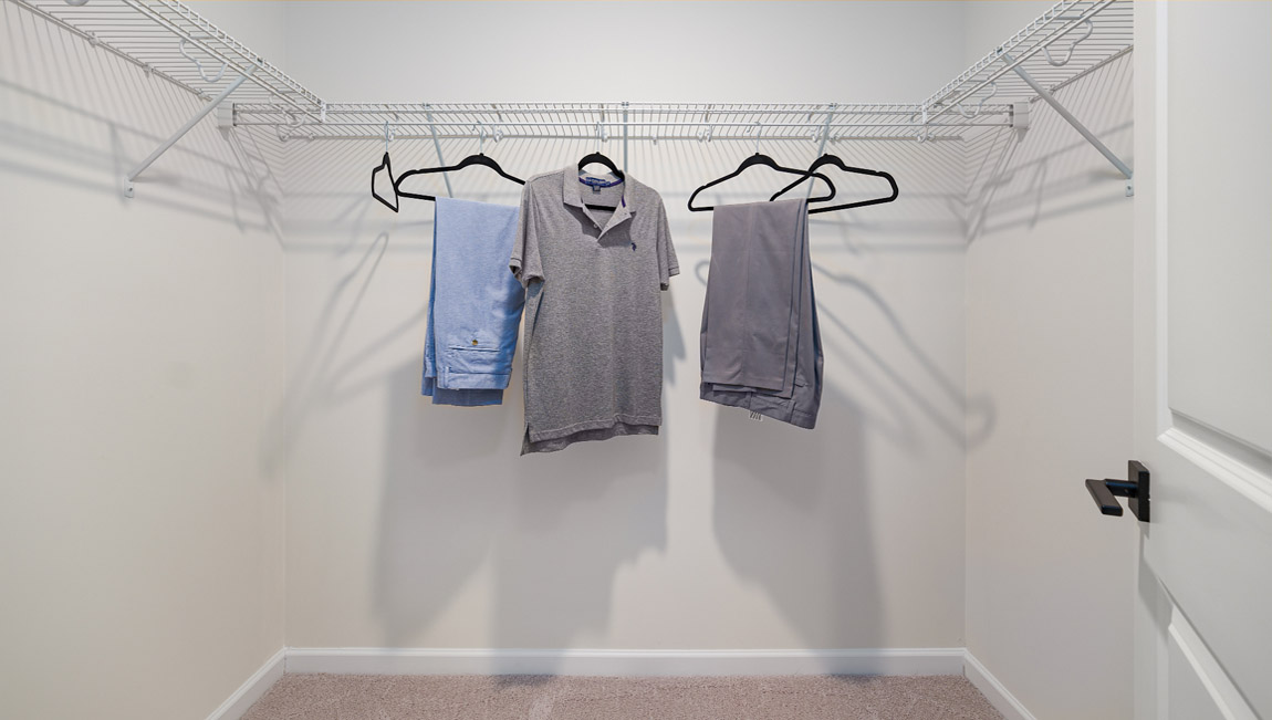 Carpeted walk in closet with built in hanger racks