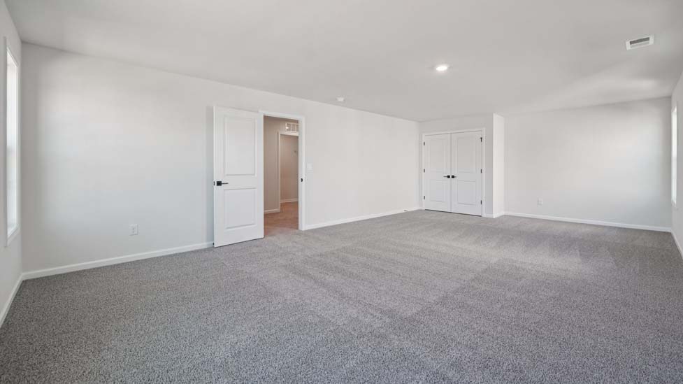 Primary carepeted bedroom with large windows