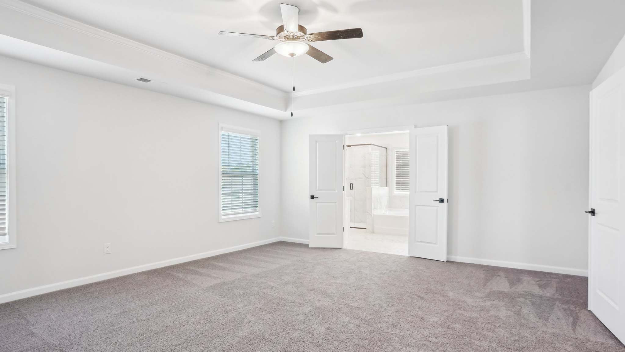 Carpeted bedroom with ceiling fan and small window