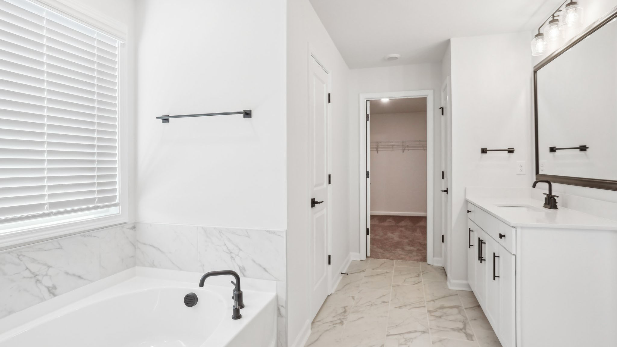 Primary bathroom with double sink vanity, brown cabinets, large bathtub, and separate standing glass door shower