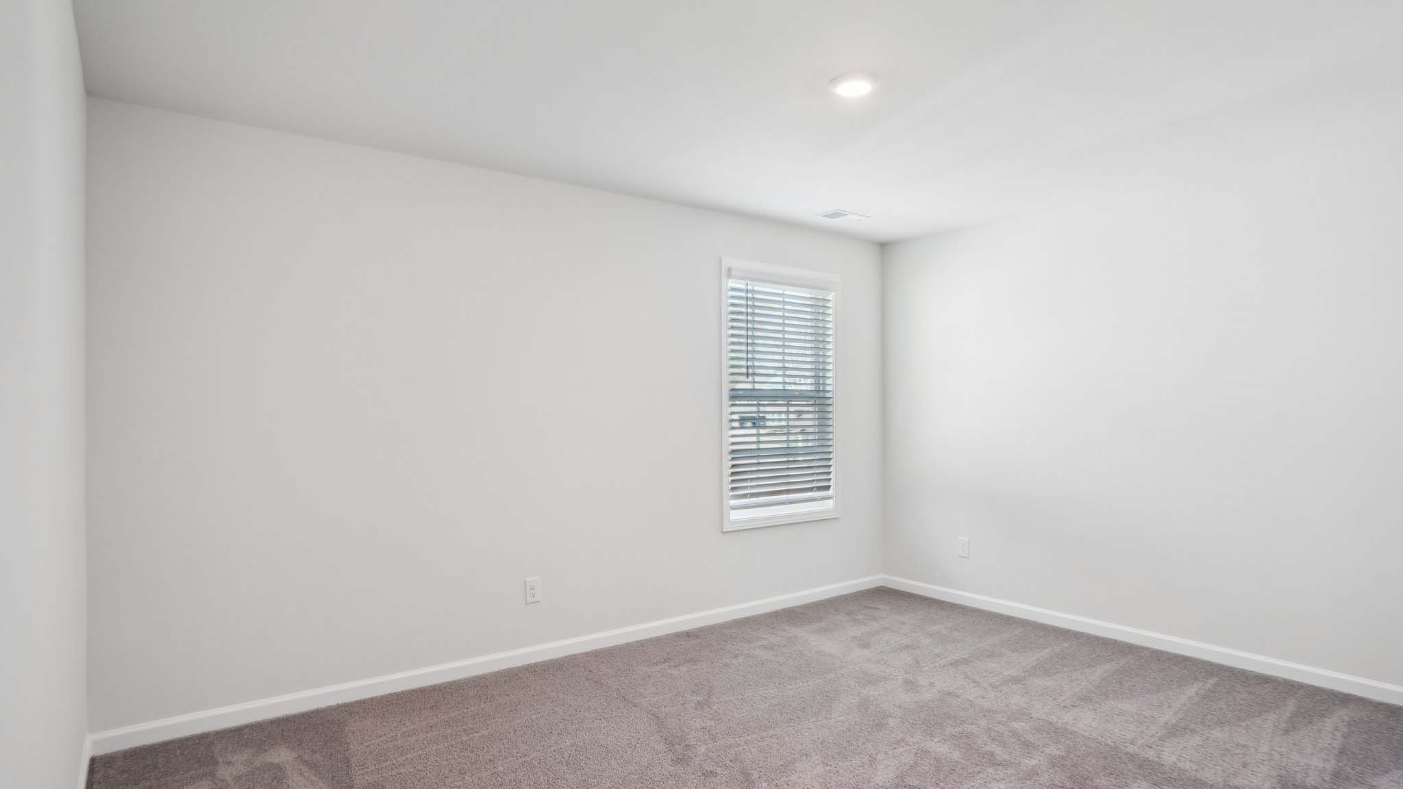 Carpeted bedroom with ceiling fan and small window