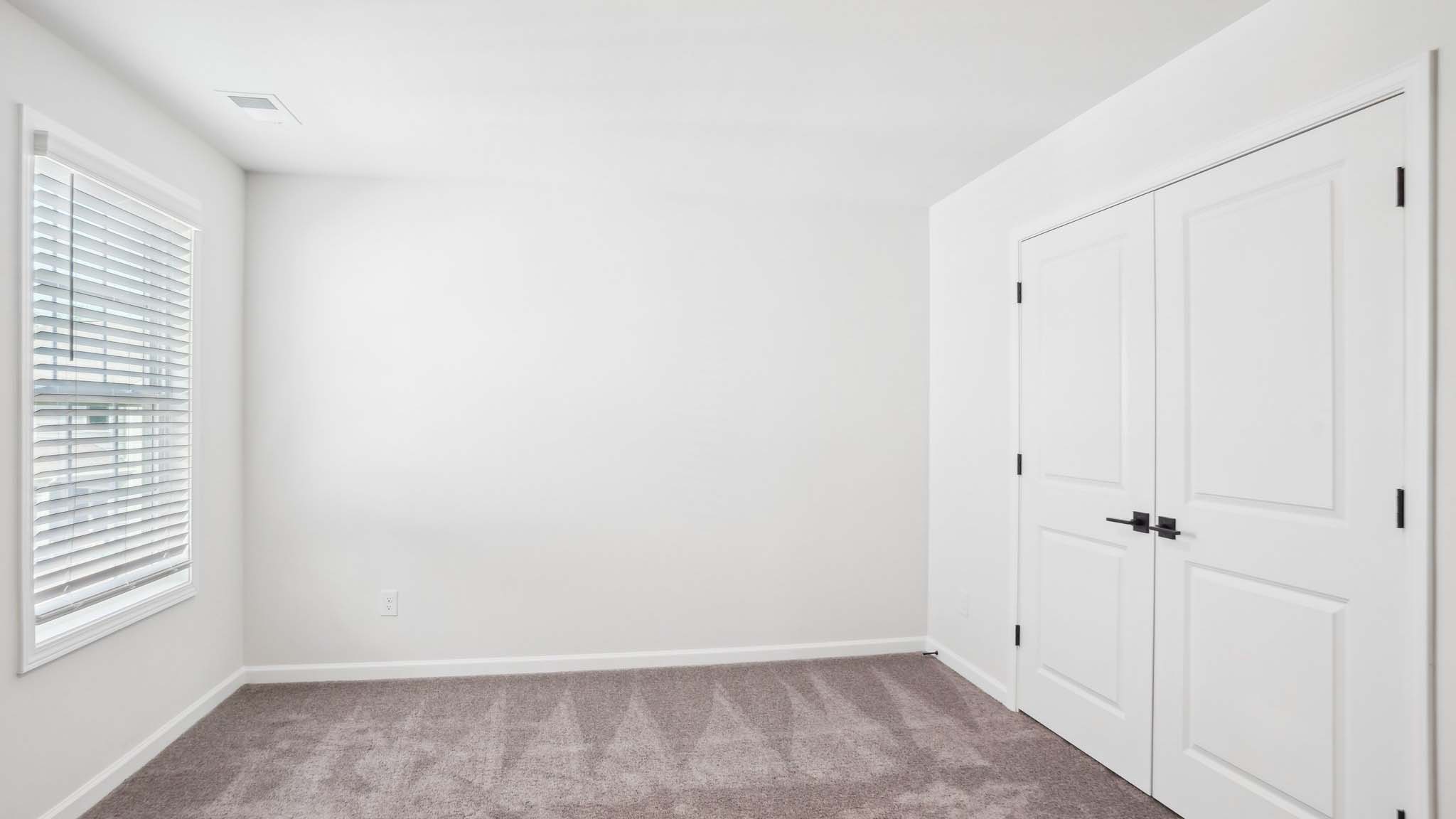 Carpeted bedroom with ceiling fan and small window