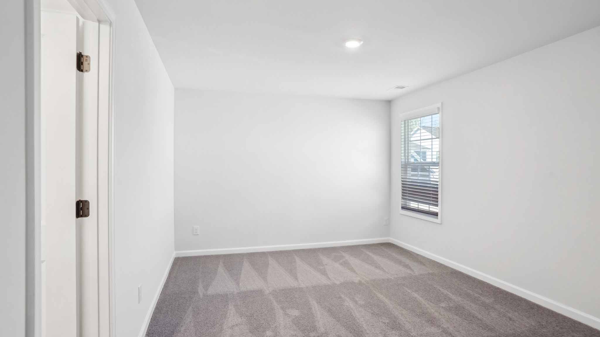 Carpeted bedroom with ceiling fan and small window