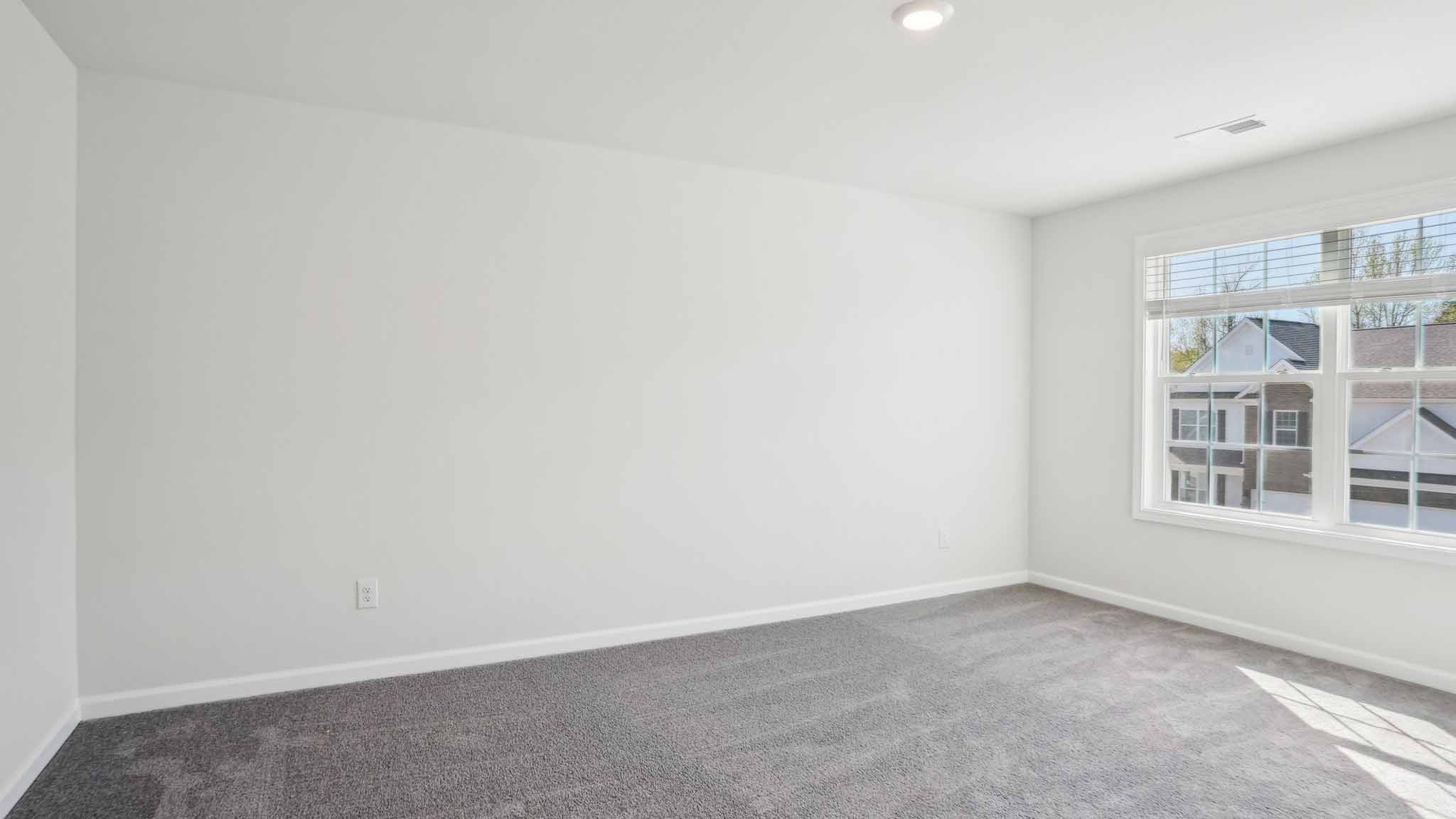 Carpeted bedroom with ceiling fan and small window