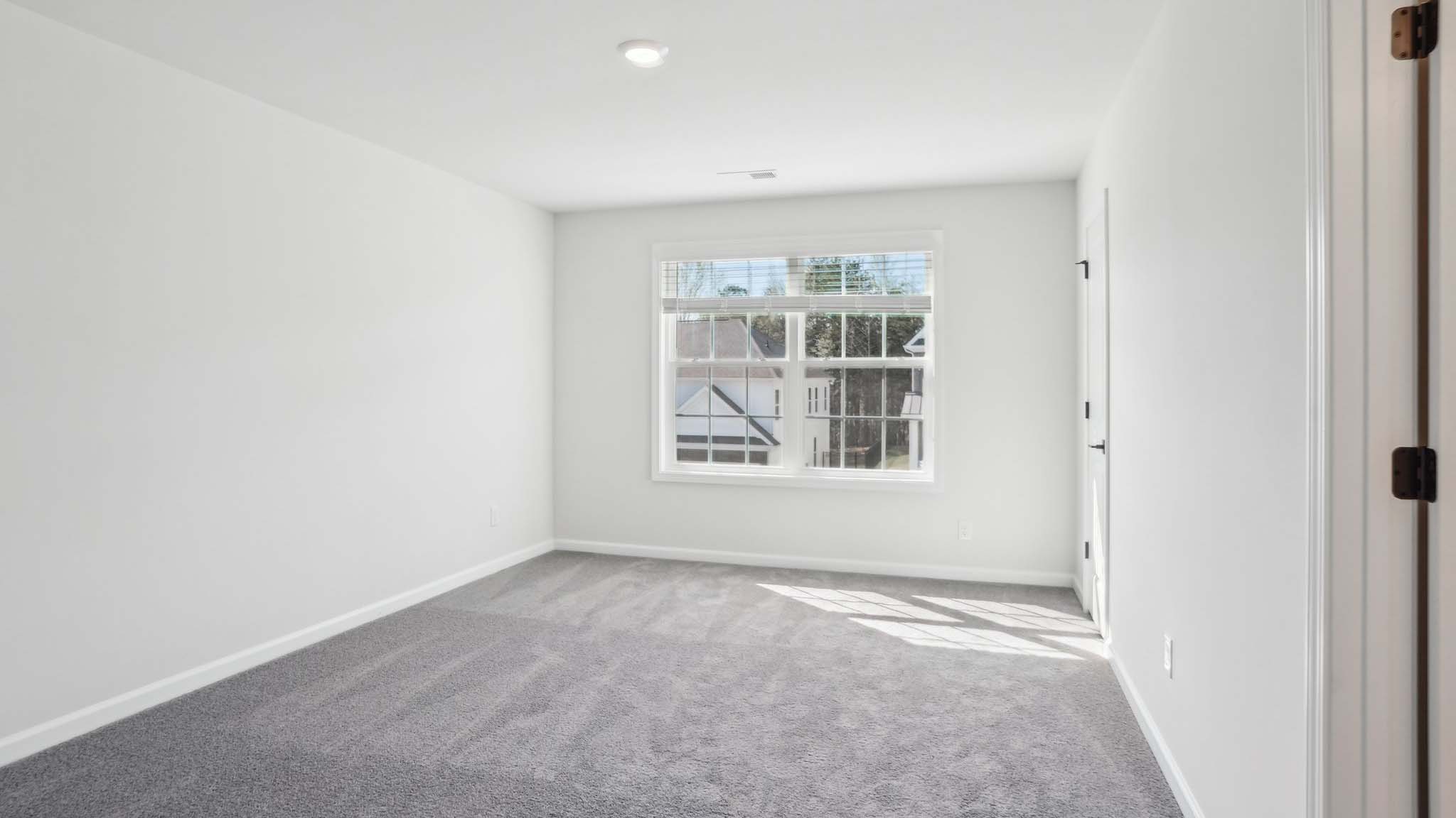 Carpeted bedroom with ceiling fan and small window