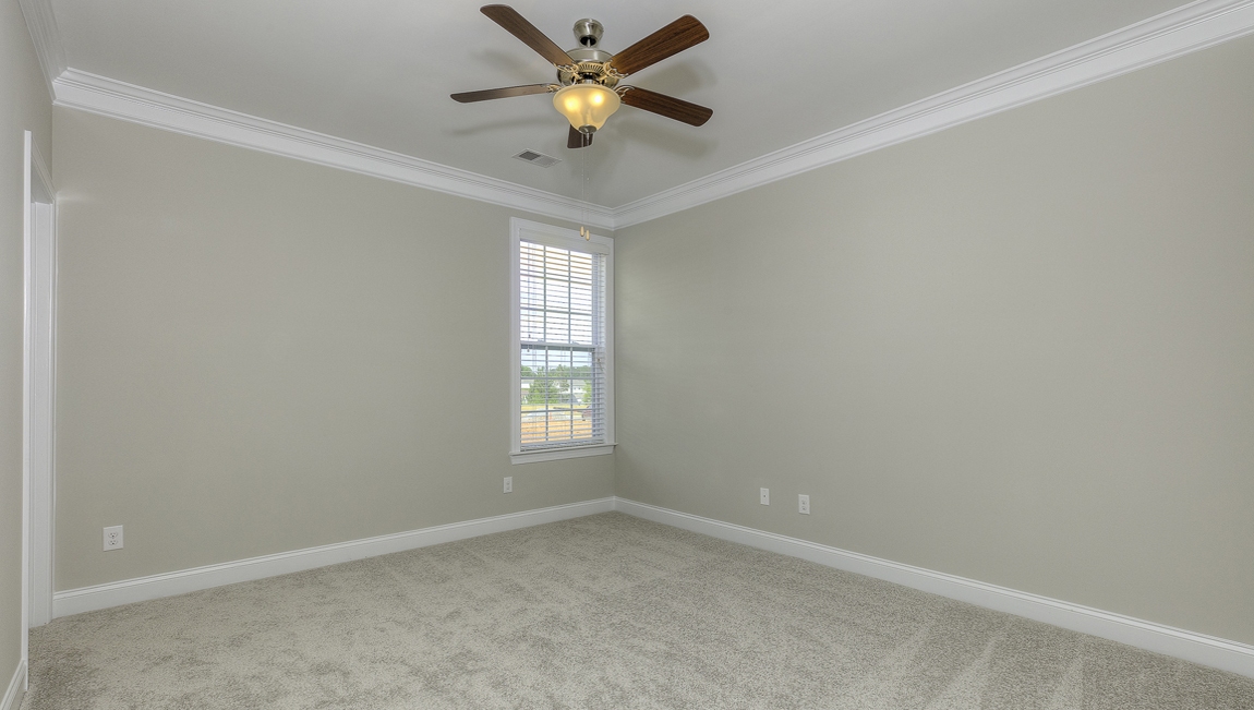 Carpeted bedroom with ceiling fan and small window