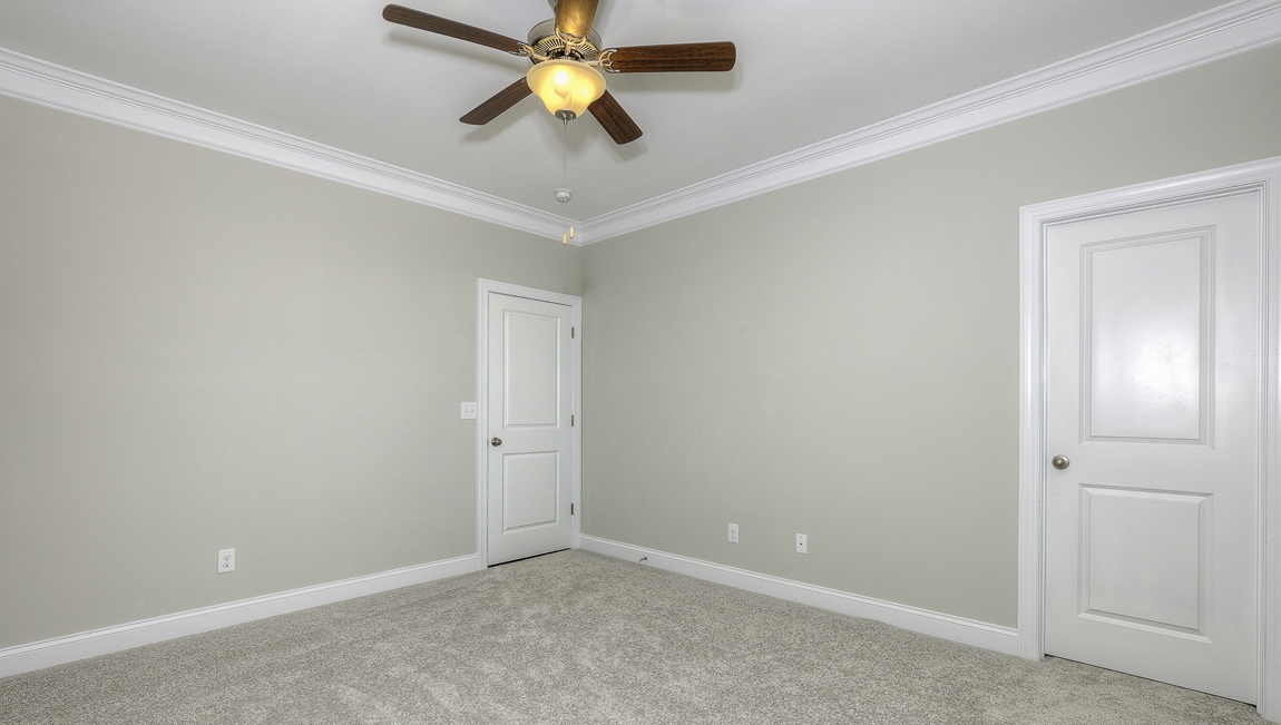 Carpeted bedroom with ceiling fan and small window