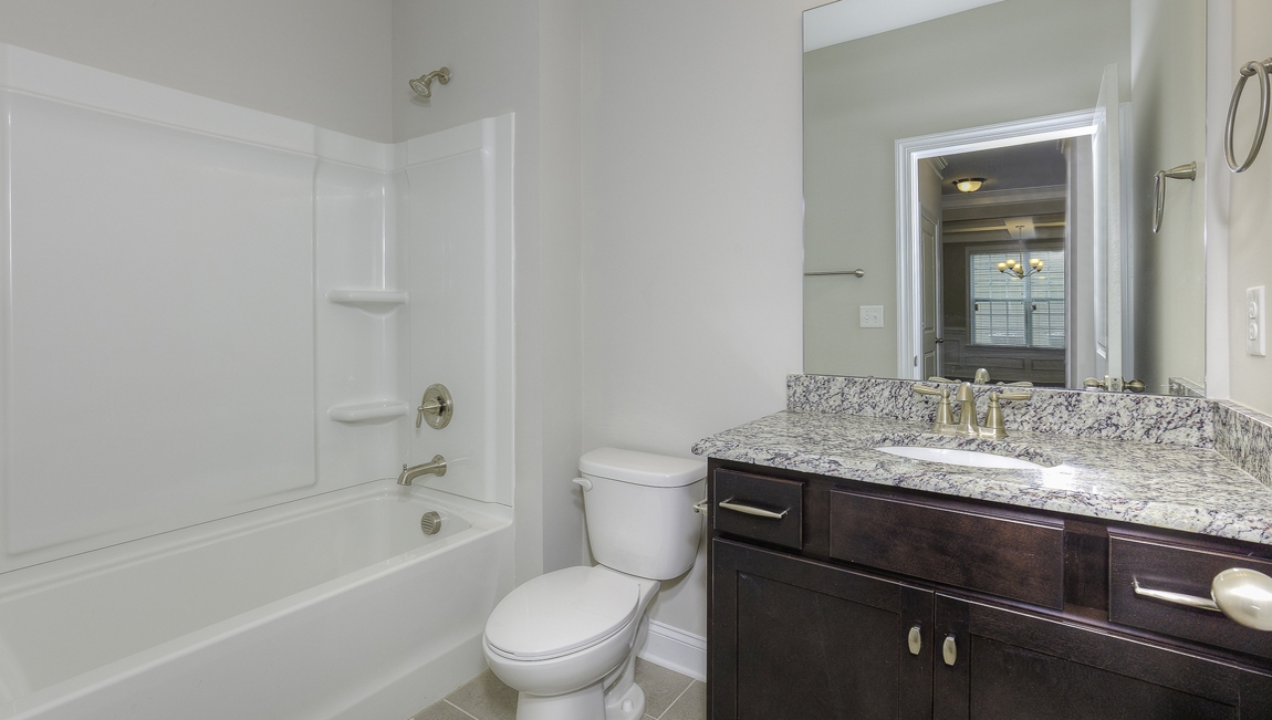 Bathroom with brown cabinets, and a bathtub shower combination