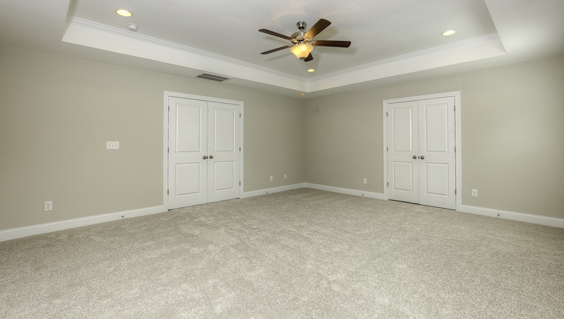 Primary bedroom with carpet, ceiling fan and two large windows