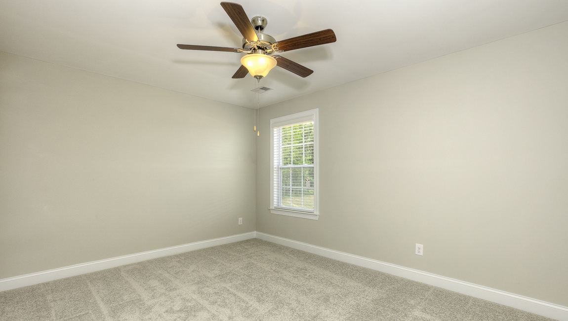 Carpeted bedroom with ceiling fan and small window