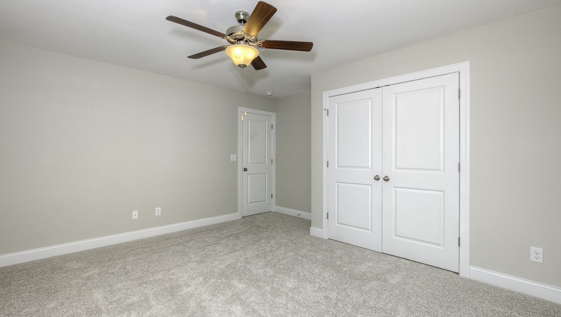 Carpeted bedroom with ceiling fan and small window