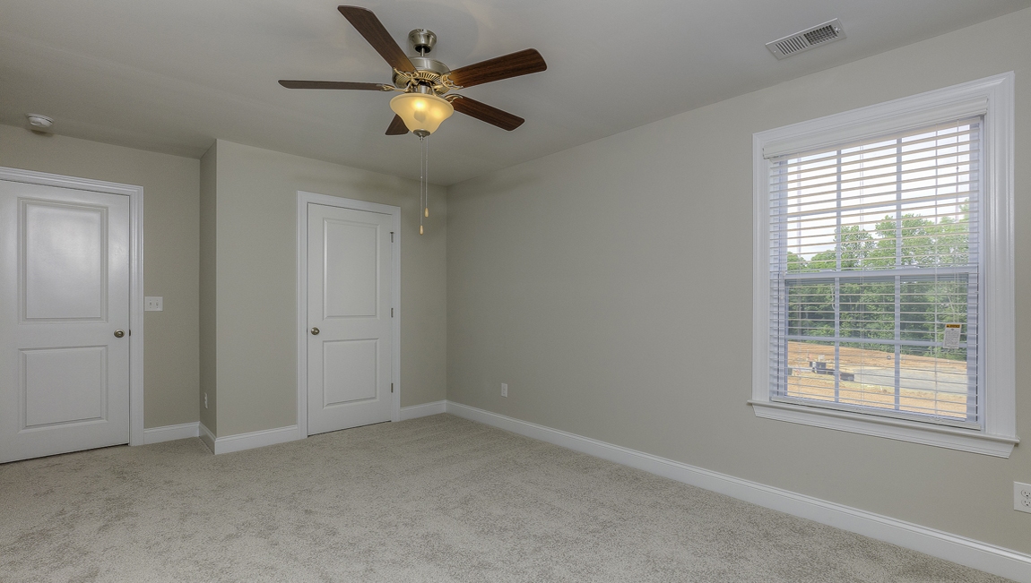 Carpeted bedroom with ceiling fan and small window